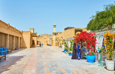 DUBAI, UAE - MARCH 2, 2020: The small square in Al Bastakiya (Al Fahidi) neighborhood with clay houses and cozy cafe, decorated with blooming bougainvillea bushes, on March 2 in Dubai clipart