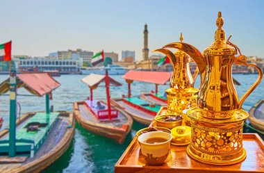 Dubai Deresi 'nin kıyısındaki abra botları manzaralı geleneksel Arap pirinç dallah kahve demliğinin tadını çıkarın.
