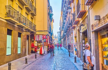 GRANADA, SPAIN - SEPTEMBER 25, 2019: Enjoy the shopping, walking narrow Calle San Jeronimo street, with rows of historical edifices and huge dome of St Justus and Pastor Basilica on background, on September 25 in Granada clipart
