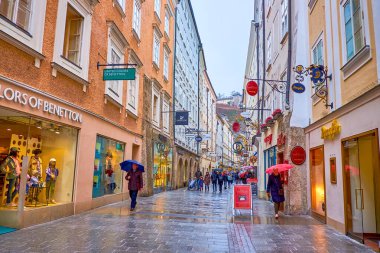 SALZBURG, AUSTRIA - 1 Mart 2019: Altstadt 'ın ana alışveriş alanı olan dar Getreidegasse, 1 Mart' ta Salzburg 'da turist mağazaları ve restoranları olan yüksek tarihi evlerle dolu.