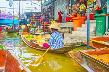 DAMNOEN SADUAK, THAILAND - 13 Mayıs 2019: Damnoen Saduak 'taki Ton Khem yüzer pazarında muz, papaya, durian ve mango yığınlarıyla dolu eski bir meyve satıcısı (tekne)