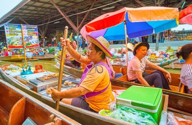 DAMNOEN SADUAK, THAILAND - MAY 13, 2019: The sailing sampan (boat) of the seafood vendor, offering grilled squids, prawns and fresh fruits,  in Ton Khem floating market, on May 13 in Damnoen Saduak clipart