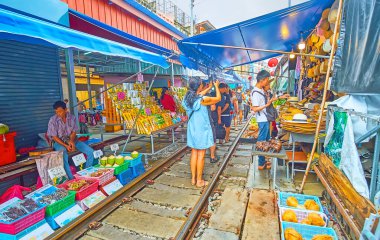 MAEKLONG, THAILAND - 13 Mayıs 2019: Turistler ve ziyaretçiler Maeklong Demiryolu Pazarı boyunca yürür, resim çeker ve 13 Mayıs 'ta Maeklong' da taze meyve ve diğer yiyecekleri seçerler.