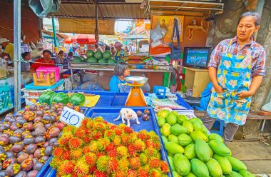 MAEKLONG, THAILAND - 13 Mayıs 2019: Küçük kedi yavrusu 13 Mayıs 'ta Maeklong' da, Maeklong Demiryolu Marketi 'ndeki bir meyve tezgahının rambutanları ve mangosenleriyle tepside oynuyor