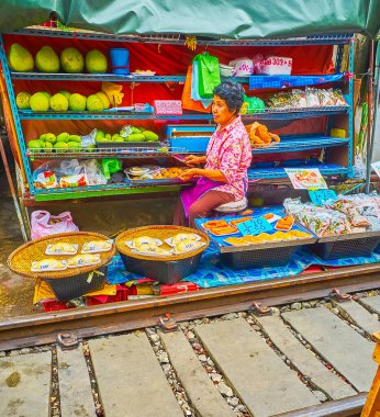MAEKLONG, THAILAND - 13 Mayıs 2019: Maeklong Demiryolu Marketi 'nin küçük meyve tezgahı 13 Mayıs' ta Maeklong 'da durian, Tayland otları ve baharatlar paketlenmiş yeşil papayalar sunmaktadır.