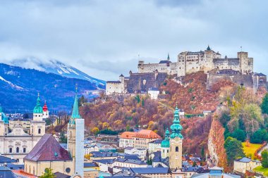 Hohensalzburg 'un ortaçağ şatosu tarihi konakları, uzun çan sesleri ve sisli Alpleri ile eski Salzburg kasabası, Avusturya.