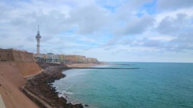 Atlantik Okyanusu kıyısında hızla akan bulutlar, Cadiz, Costa de la Luz, İspanya 'nın büyük kaya duvarları ve konutları.