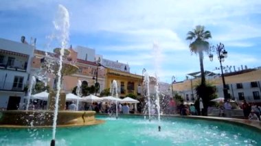 SANLUCAR, SPAIN - SEPTEMBER 22, 2019: Tarihi Plaza del Cabildo Meydanı, 22 Eylül 'de Sanlucar' da serinletici fıskiyeler, mevcut kasaba evleri ve açık hava restoranları ile popüler şehir merkezidir.