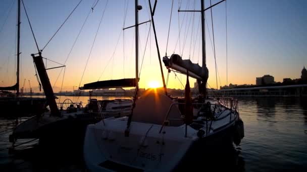 スペインのマラガ 2019年9月28日 マラガの9月28日にマラガ港で係留されている帆ヨットを通して夕日を見る — ストック動画