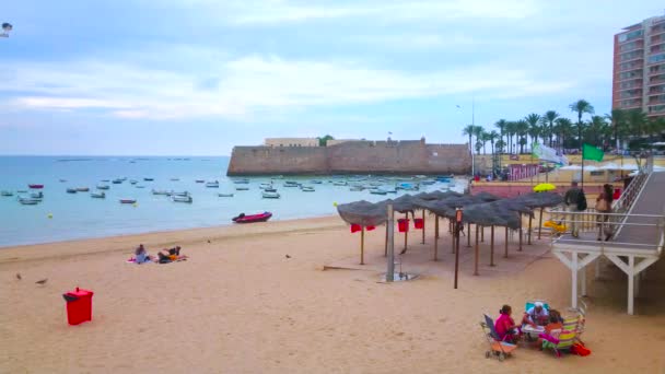 Cadiz スペイン 2019年9月21日 港に係留された漁船とサンタカタリナ砦の城壁を背景にした居心地の良い砂のラカレタビーチ Castillo 9月21日にカディスで — ストック動画