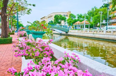 Khlong Phadung Krung Kanalı 'nın karşısındaki köprüde taş balyaları, ağaçlar, çiçek açan bougainvillea çalıları, klasik sokak lambaları, Dusit, Bangkok, Tayland
