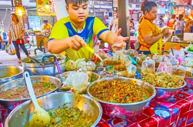 BANGKOK, THAILAND - 13 Mayıs 2019: Talad Saphan Phut pazarındaki satıcı, 13 Mayıs 'ta Bangkok' ta plastik paketlere baharatlı salata ve sos paketi yapıyor.