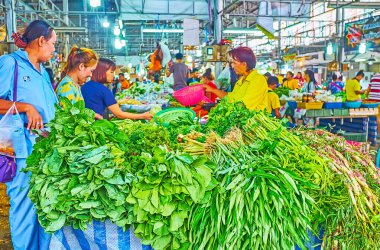 BANGKOK, THAILAND - 13 Mayıs 2019: 13 Mayıs 'ta Bangkok' ta Talad Saphan Phut pazarının üretim bölümünde bulunan yığınla yeşillik ve otla dolu tezgahtaki müşteriler