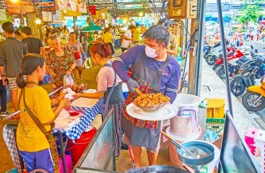 BANGKOK, THAILAND - 13 Mayıs 2019: Talad Saphan Phut pazarının aşçısı 13 Mayıs 'ta Bangkok' ta baharatlı, derin kızarmış tavuk yapar.