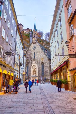 SALZBURG, AUSTRIA - 1 Mart 2019: Eski ortaçağ Burgerspitalkirche St. Blasius Kilisesi (St. Blasius Kilisesi), 1 Mart 'ta Salzburg' da ünlü Getreidegasse alışveriş sokağının sonunu tespit etti.