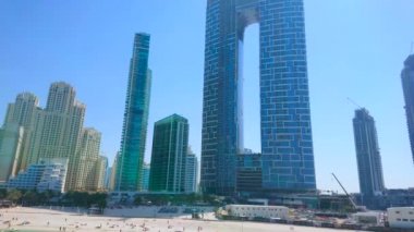 DUBAI, BAE - 7 Mart 2020: Dubai 'de 7 Mart' ta Dubai 'de JBR Marina plajında yüzen tekneler, yüzen ve güneşlenen tatilciler, fütürist gökdelenler, Jumeirah Resort gibi
