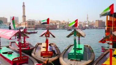 DUBAI, BAE - 2 Mart 2020: Eski ahşap abra botlar Deira kıyısındaki Dubai Deresi 'nde dalgalarda sallanıyor; 2 Mart' ta Dubai 'de Dubai' de Büyük Cami ve Bur Dubai 'nin minaresi görülüyor.