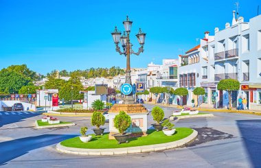 ARCOS, SPAIN - 23 Eylül 2019: The Plaza Espana Square with white house, flower bed, topiary trees and vintage street light, on Arcos