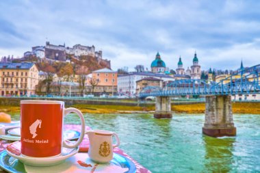 SALZBURG, AUSTRIA - 1 Mart 2019: 1 Mart 'ta Salzstadt ilçesinde Salzach nehrinin kıyısındaki açık bir kafede akşam kahvesi