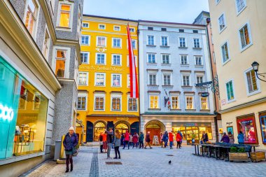 SALZBURG, AUSTRIA - 1 Mart 2019 'da kalabalık Getreidegasse caddesi Mozart' ın doğduğu yer olan tarihi sarı Hagenauerhaus 'a, 1 Mart' ta Salzburg 'da saygı duyulan kent simgesine sahiptir.