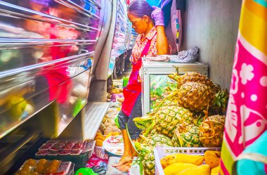 MAEKLONG, THAILAND - MAY 13, 2019: The train is riding through the cramped Maeklong Railway Market (Talad Rom Hoop) and the vendor needs to lean against the wall, on May 13 in Maeklong clipart