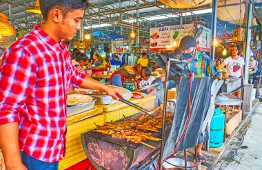 BANGKOK, THAILAND - 13 Mayıs 2019: Talad Saphan Phut pazarının küçük tezgahının satıcıları 13 Mayıs 'ta Bangkok' ta baharatlı balık, deniz ürünleri ve domuz barbeküsü pişirdiler.