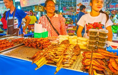 BANGKOK, THAILAND - 13 Mayıs 2019: Talad Saphan Phut pazarının gülümseyen satıcıları, 13 Mayıs 'ta Bangkok' ta ızgara balık, baharatlı soslu domuz eti ikram ettiler