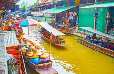 DAMNOEN SADUAK, THAILAND - 13 Mayıs 2019: Damnoen Saduak khlong 'daki turist örnekleri (botlar), Damnoen Saduak' ta 13 Mayıs 'ta yiyecek, hediyelik eşya ve aksesuar satıcılarıyla birlikte yüzüyor.