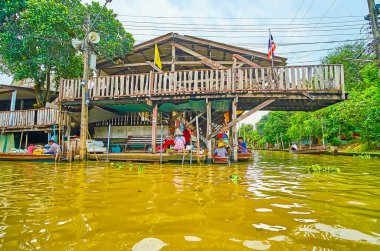 DAMNOEN SADUAK, THAILAND - 13 Mayıs 2019: Damnoen Saduak yüzen pazarındaki eski stilt evi Damnoen Saduak 'ta 13 Mayıs' ta sampan teknelerini demirlemek için sırıkla kaplanmıştır.