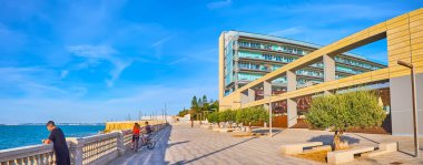 CADIZ, SPAIN - 23 Eylül 2019: Okyanus kıyısındaki gezinti alanının modern Parador de Cadiz oteli manzaralı panoraması, arka planda zeytin ağaçları ve ortaçağ kalesi hattı, 23 Eylül 'de Cadiz' de