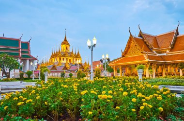 Akşamın güzelliğinin tadını çıkarın Mahajetsadabadin parkında marigold çiçek yatakları, klasik sokak lambaları, Royal Pavilion ve Loha Prasat tapınağı arka planda, Bangkok, Tayland