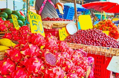 Mahanak Fruit Market, Bangkok, Tayland 'daki küçük çiftçi tezgahında egzotik ejderha meyveleri (pitaya), kiraz erikleri ve rambutanlar yığını