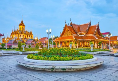 Gece boyunca Mahajetsadabadin parkında kadife çiçekleri, orkideler, çalı çalıları, saksılarda bitkiler, Royal Pavyonu ve Wat Ratchanatdaram, Bangkok, Tayland