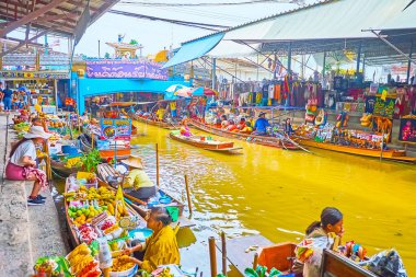 DAMNOEN SADUAK, THAILAND - MAY 13, 2019: The streetscape of Damnoen Saduak floating market with large trade pavilions, souvenir stalls, narrow khlong, bridge and food boats, on May 13 in Damnoen Saduak clipart
