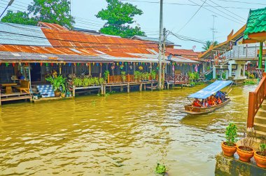 DAMNOEN SADUAK, THAILAND - 13 Mayıs 2019: Damnoen Saduak yüzer pazarının khlong 'u Damnoen Saduak' ta 13 Mayıs 'ta tahta evler, ahşap pavyonlar, misafir evleri ve tezgahlarla doludur.