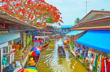 DAMNOEN SADUAK, THAILAND - 13 Mayıs 2019 Damnoen Saduak yüzen pazarının renkli şemsiyeleri ve botları, çatıları üzerinde dar khlong ve çiçek açan alev ağacıyla 13 Mayıs 'ta Damnoen Saduak' ta