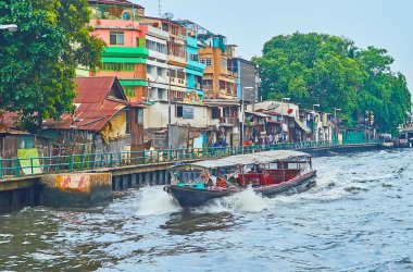 BANGKOK, THAILAND - 13 Mayıs 2019: Eski ahşap feribot Bangkok 'ta 13 Mayıs' ta Khlong Maha Nak Kanalı 'ndaki gecekondu ve harap evler boyunca yüzer.