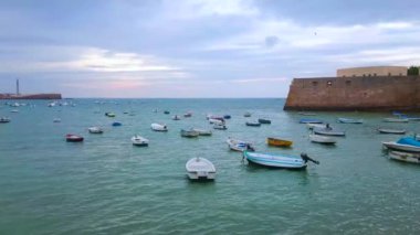 CADIZ, SPAIN - 21 Eylül 2019: 21 Eylül 'de Cadiz' de San Sebastian ve Santa Catalina ortaçağ kaleleri arasında kıyıya demirlemiş La Caleta plajı ve limanı panoraması