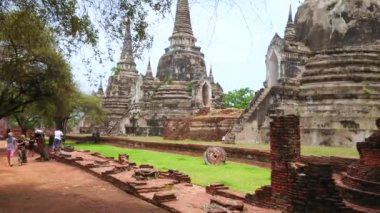 AYUTTHAYA, THAILAND - 14 Mayıs 2019: Turistler 14 Mayıs 'ta Ayutthaya' da, kraliyet sarayı ve kült nesnelerinin kalıntılarını içeren Wat Phra Si Santhe kompleksinin gölgeli sokaklarında yürürler.