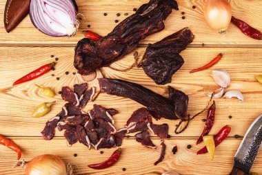 Ahşap arka planda kurutulmuş et, sebzeler ve av bıçağı.