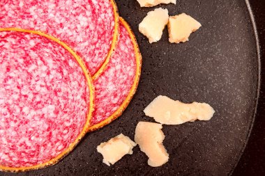 Yakın plan füme sosis ve siyah taş tabakta parmesan peyniri.