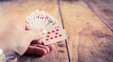 124 numaralı eski ahşap masada kağıt oynayan bir el. Gamblin.