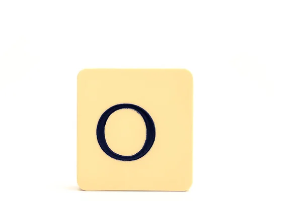 Mörk bokstav O på en blekt gul fyrkantig block isolerad på vit ba — Stockfoto