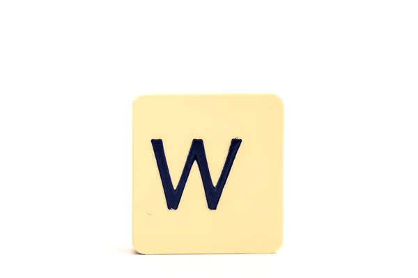Tmavé písmeno W na světle žlutém čtvercovém bloku izolovaném na bílém ba — Stock fotografie