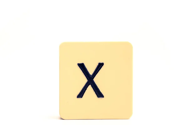 Tmavé písmeno X na světle žlutém čtvercovém bloku izolovaném na bílém ba — Stock fotografie