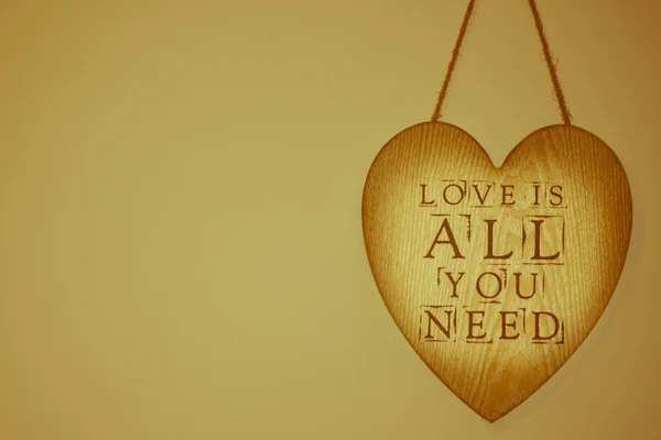 İhtiyacınız olan tek şey, duvarda asılı olan tahta bir kalpte aşk. — Stok fotoğraf