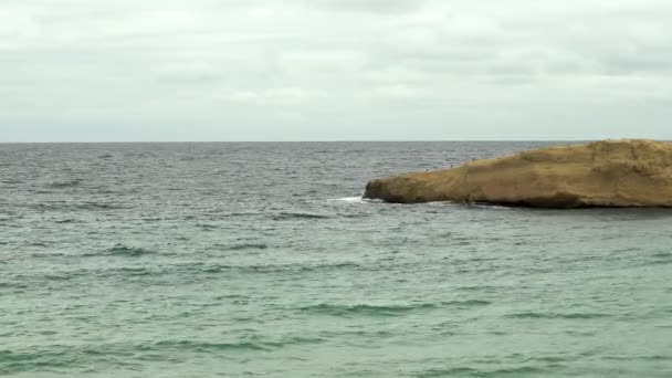 Dalgalar denizde kayalık bir adaya vuruyor. Akdeniz 'de fırtına var. Deniz turkuazdır.. — Stok video