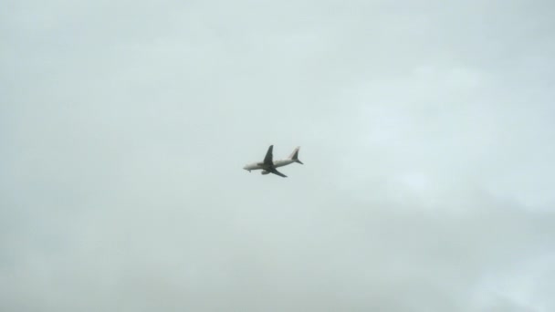 Sisli gri gökyüzünde bir yolcu uçağı uçuyor. Aşağıdan görüntüle. — Stok video