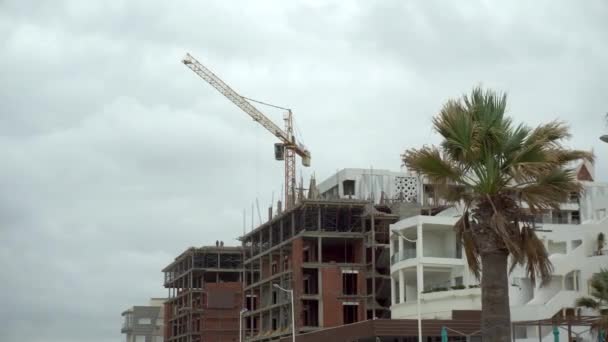 A crane is building a house in a hot country. Overcast. Unfinished house — Stockvideo