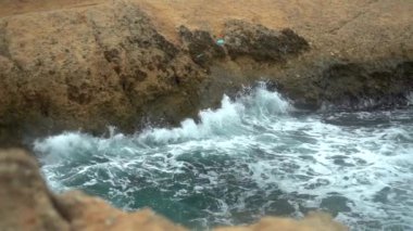 Dalgalar kayalara çarpıyor. Akdeniz 'de fırtına var. Deniz turkuazdır. Yavaş çekim.